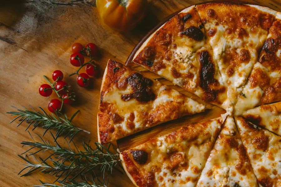 Wood-fired pizza on a board with cherry tomatoes